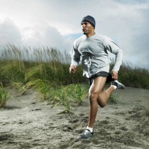 A man running on the beach in shorts.