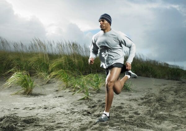 A man running on the beach in shorts.