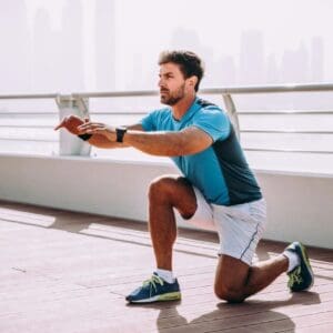 A man squatting on the ground in front of a city skyline.