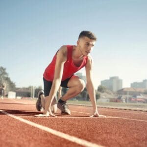 A man is crouching on the track in a race.