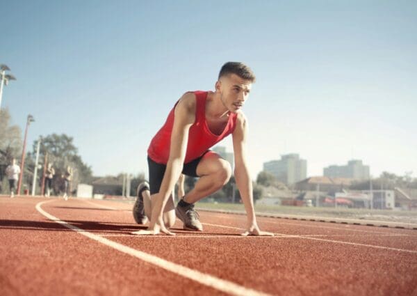 A man is crouching on the track in a race.