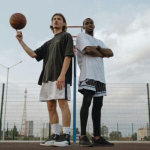 Two men are standing on a court with a basketball.