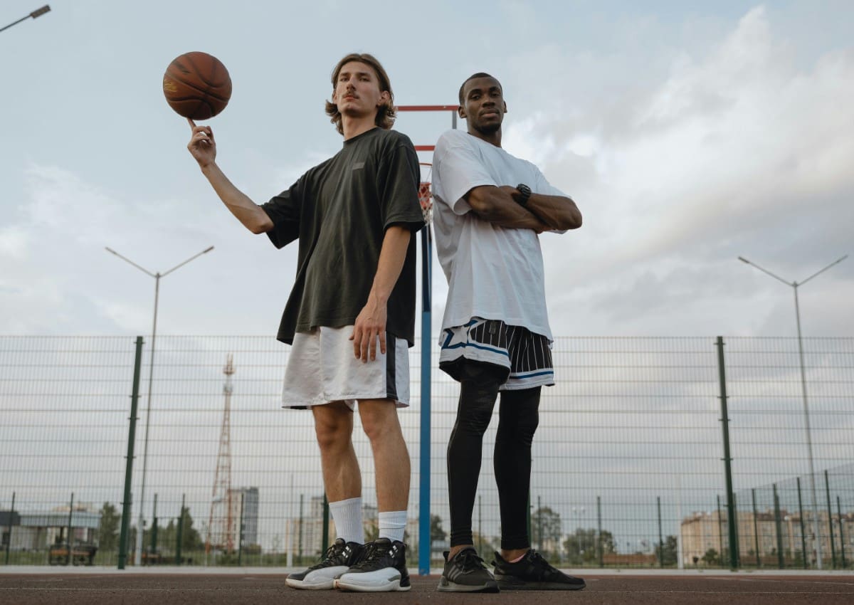 Two men are standing on a court with a basketball.